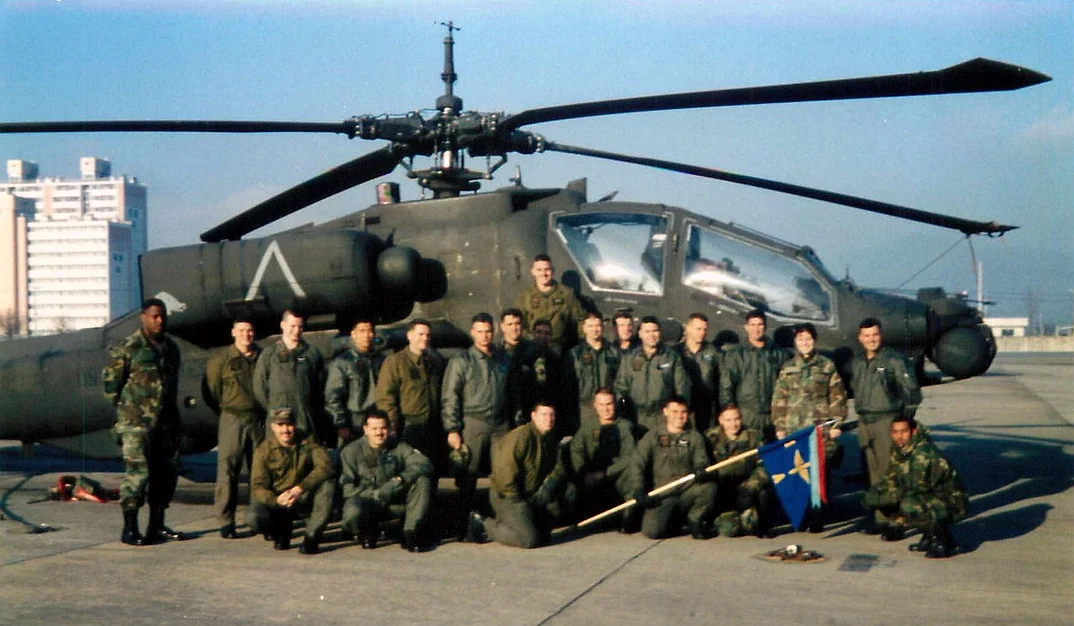 Shannon Huffman Polson with her Apache company in front of an AH-64 Apache helicopter