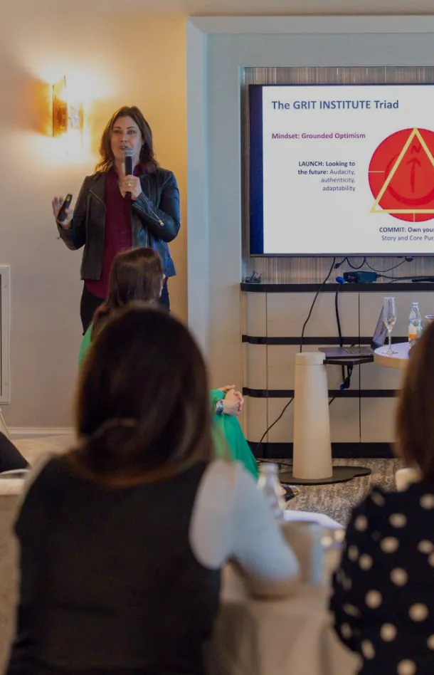Woman presenting a leadership slide to a seated audience.
