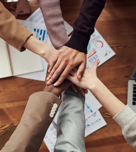 Team members stacking hands together over a desk