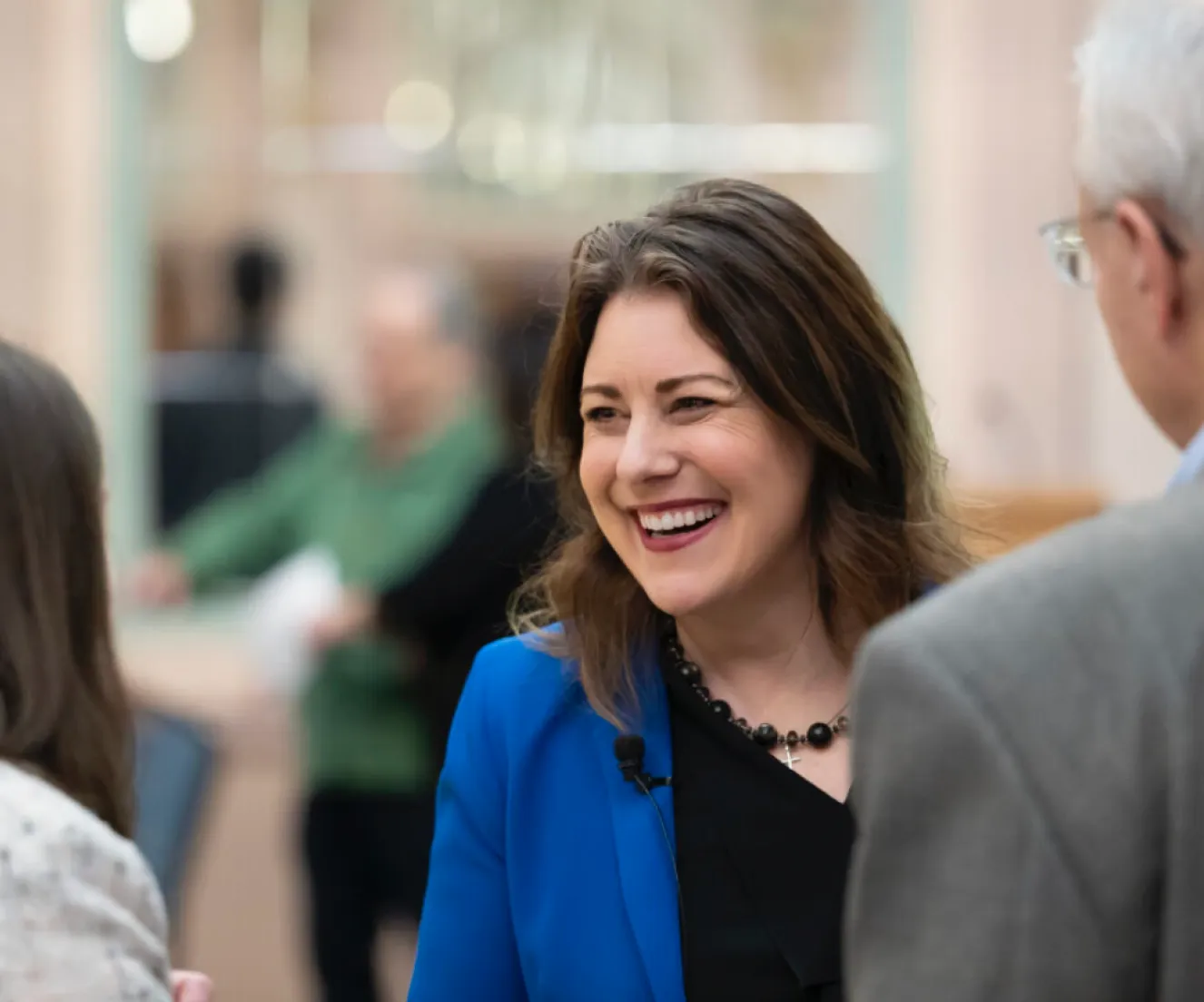 Woman smiling while networking with people at an indoor event