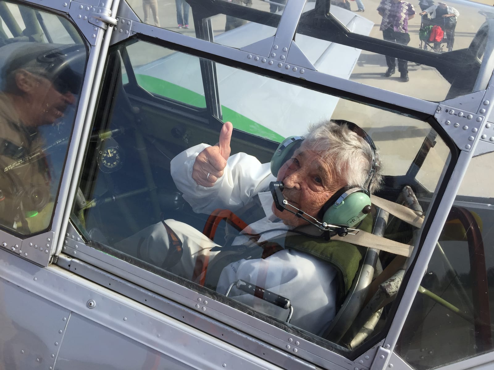 A pilot gives a thumbs-up from the cockpit of a vintage aircraft