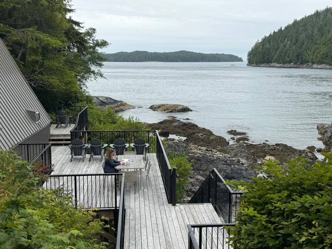 Shannon Huffman Polson writing on a deck above a forested coastline